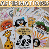 Children's affirmation cards with cartoon animals and motivational phrases on a wooden surface.
